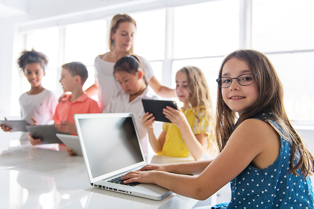 Classe primaire enfants avec ordinateur et tablettes
